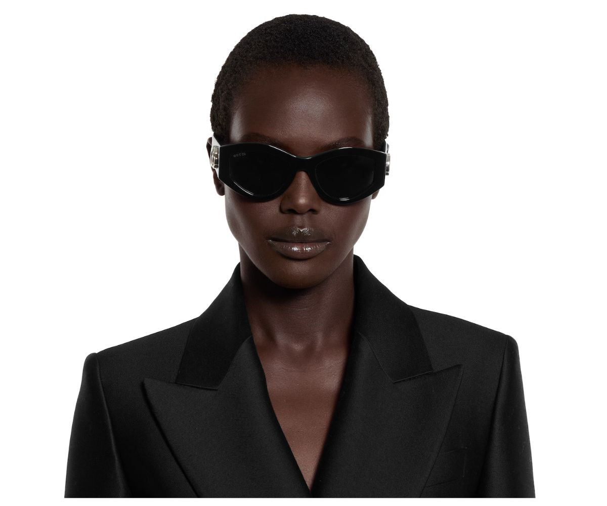 Gucci black cat-eye sunglasses with silver accents, worn by model in black blazer